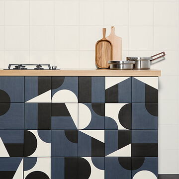 quadratische Fliesen mit geometrischen Formen für die Kücheninsel, weiß Fliesen an der Wand und schwarze auf dem Fußboden