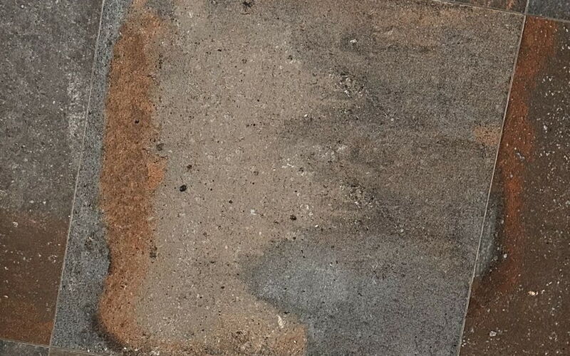 Verbund mehrere quadratischer grauer Bodenfliesen, teilweise mit rostähnlichen Effekten