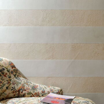 in weiß-beige Streifen verputzte Wand, davor ein Sessel mit Zeitschrift