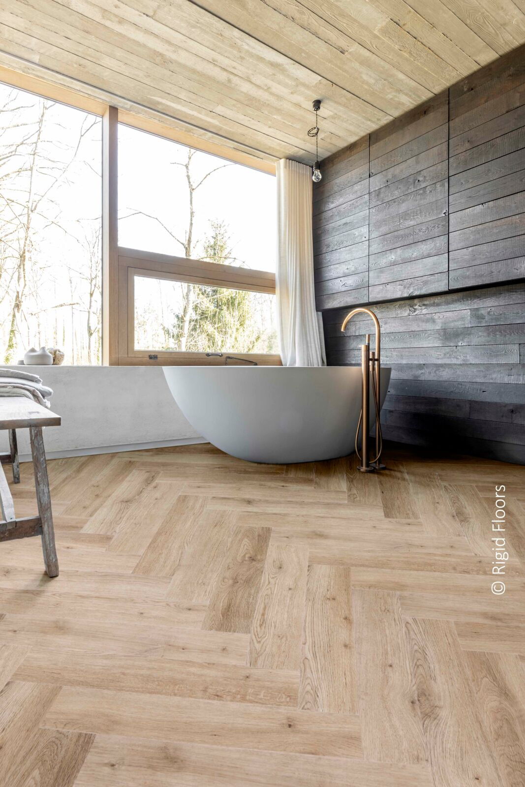 großzügiges Bad mit Holz-Elementen und freistehender Badewanne auf Fußboden in Holz-Optik mit großem Fischgrätenmuster