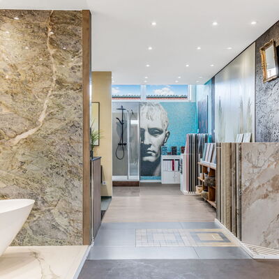 Blick in die Fliesenausstellung mit Badewanne, Dusch-Armaturen und Fliesenmustern hauptsächlich in Stein-Optik