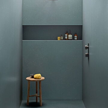begehbare Dusche mit grauen, großen Fliesen und Ablage mit Dusch-Utensilien, dazu ein Holzhocker
