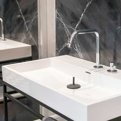 weißes, eckiges Waschbecken mit dunkelgrauen Wandfliesen
