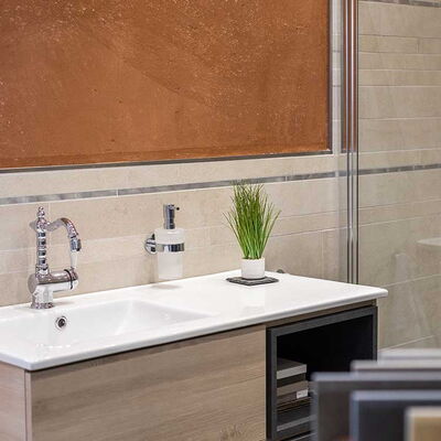 weißes, eckiges Waschbecken mit Ablagefläche daneben, Unterschrank aus hellem Holz und beige Wandfliesen