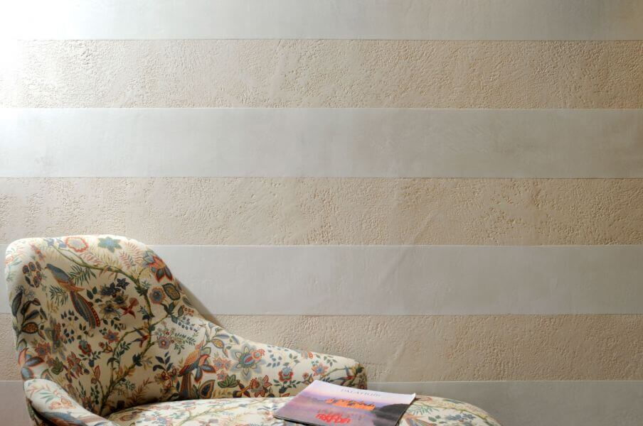 in weiß-beige Streifen verputzte Wand, davor ein Sessel mit Zeitschrift