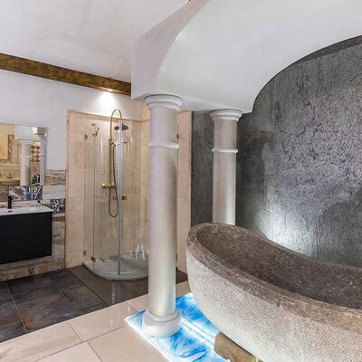 Vordergrund mit rustikalem, steinernem Becken umrahmt von Säulen; im Hintergrund weitere Teile der Ausstellung