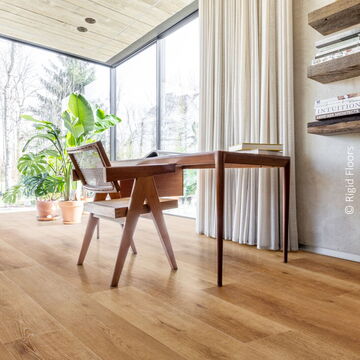 Wohnraum mit großer Fensterfront und Holzschreibtisch und -stuhl auf braunem SPC-Fußboden in Holzoptik