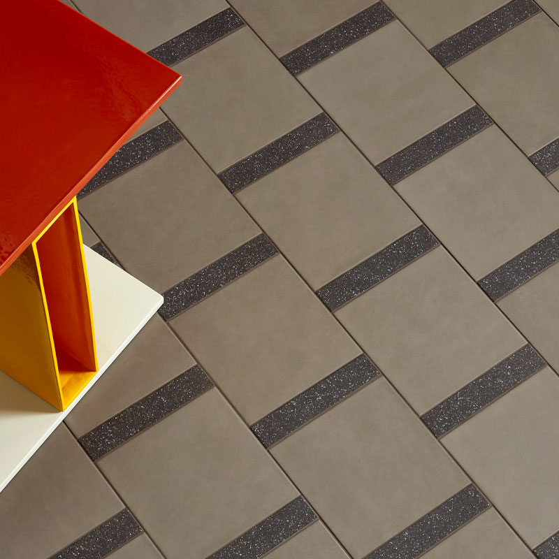 Mutina Designerfliese Time als Bodenfliese verlegt mit einem rot-gelben Tisch im Anschnitt