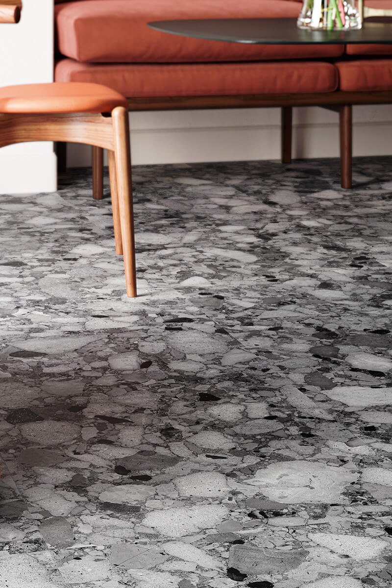 Schwarz-weiß gesprenkelten Fliese in Terrazzo-Optik mit Sofa im Hintergrund