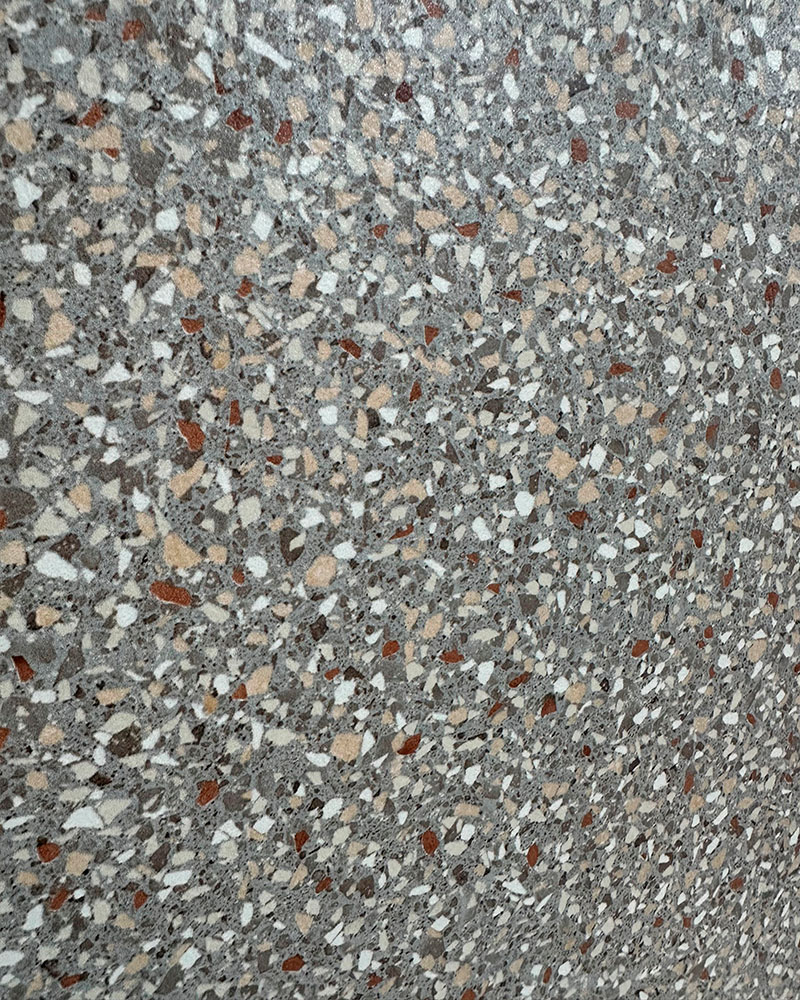 Nahaufnahme einer grauen Fliese in Terrazzo-Optik mit weißen und roten Sprenkeln
